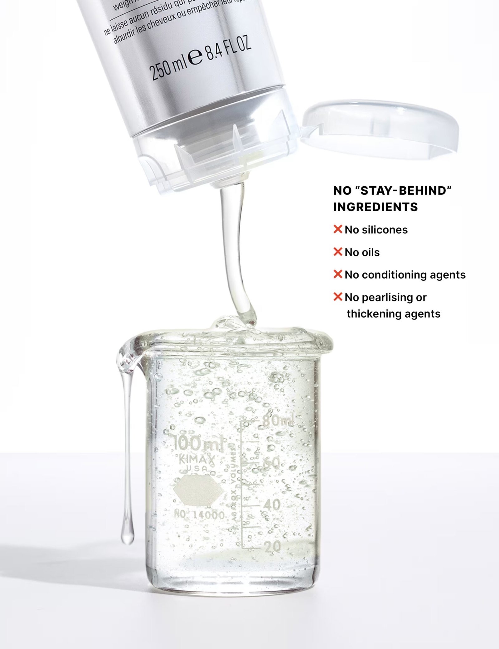 Hair extension safe shampoo bottle being squeezed into a clear glass measuring beaker next to a list of ingredients to avoid, which includes no silicones, no oils, no conditioning agents, and no pearlising or thickening agents.