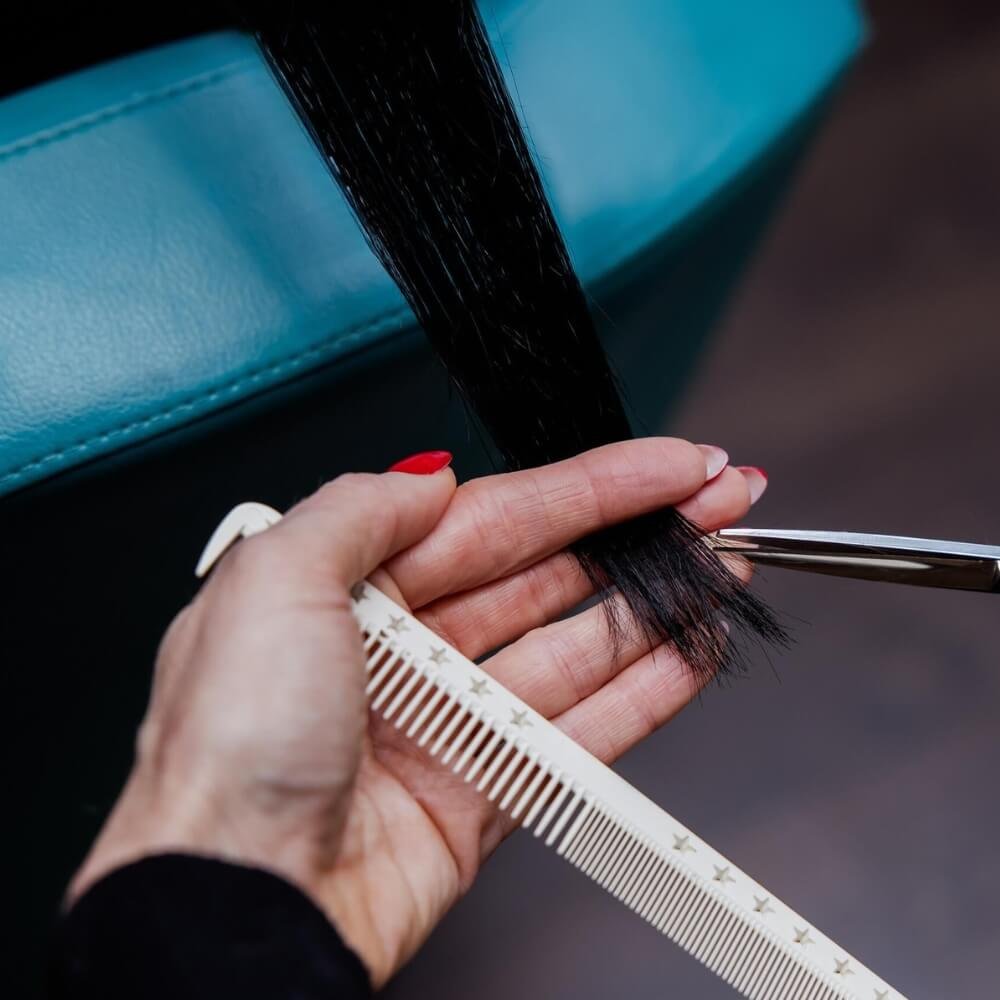 Professional hair stylist cutting clip in hair extensions